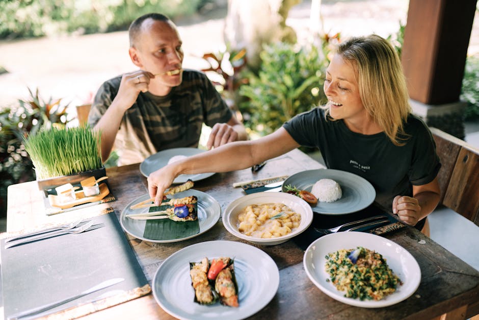 A couple enjoying a variety of Asian dishes outdoors at a cozy table setting
