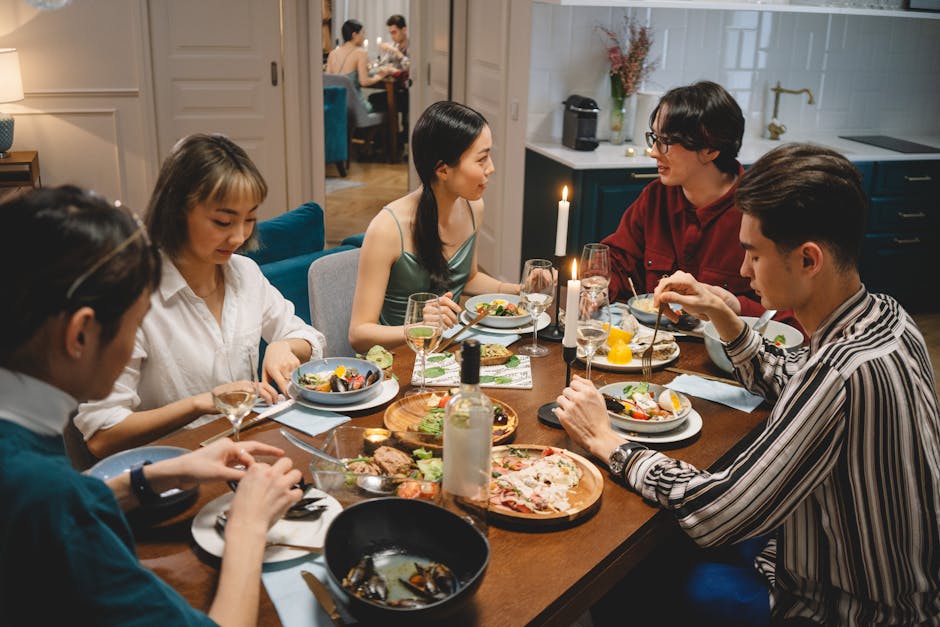 A diverse group of friends sharing dinner at a cozy dining table with wine and lighted candles.